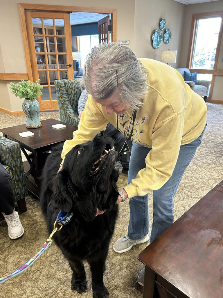 Elderly woman bonding with a dog during a canine comfort session at the senior living community.