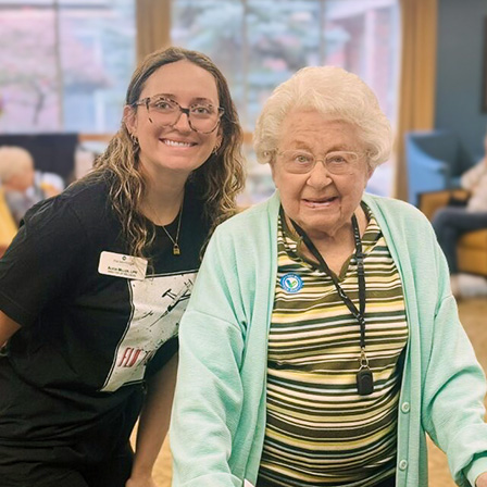 A team member and senior woman smile during a relaxed moment at The KentRidge Senior Living.