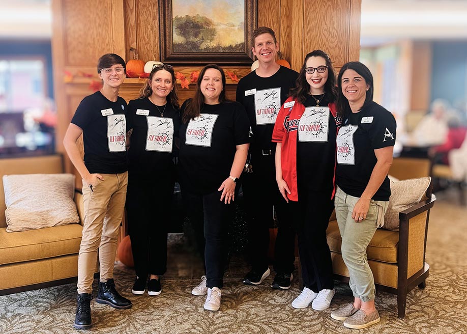 Team members wearing "flu fighters" shirts pose while smiling.