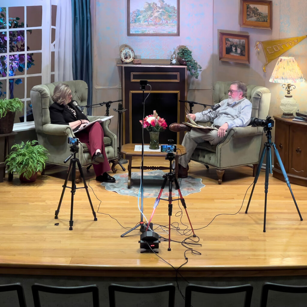 Elizabeth Thompson and Charlie Johnson record the Thoughtful Connections memory care podcast on a staged living room set with microphones and cameras.